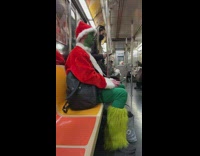 Guy sits in green paint and Santa outfit on train 