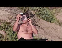 Guy applies sunscreen onto face at beach