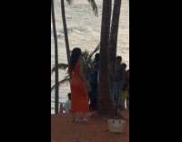 Woman in orange dress tripod beach photoshoot