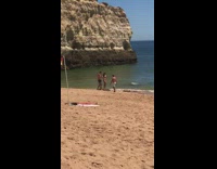 Multiple girls pose beach red yellow flag 