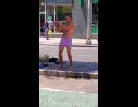 Man plays flute in purple boxers and thrusts hips on street divider