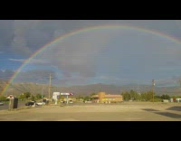 Rainbow in sky gas station grey clouds