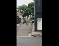 Woman sits criss cross on ground in alley in front of mural
