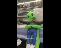 Green alien costume on subway