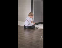 Baby riding roomba around floor 