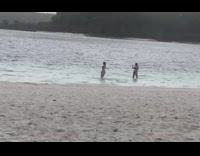 Two girls take photos in beach water 