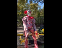Kid touching teddy bear held by scary clown statue 