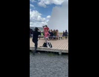 Pink shirt girl exercises by geyser tourists 