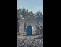 Woman in bikini poses while man holds phone