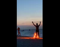 guy hands up bonfire beach