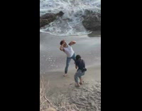 Man in white sleeveless top dramatic poses by the beach