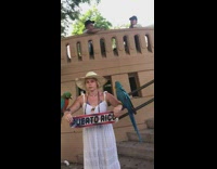 Woman in white dress poses with parrots scared