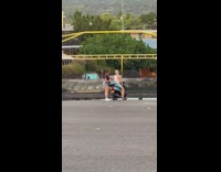 Blonde girl ride motorcycle near water overcast