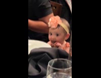 Baby holds and eats steak inside restaurant