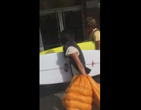 Guy follows two people with surfboards 