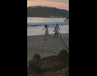 Couple in white outfit hold hands and run at the beach