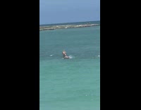 Woman paddles surfboard while another woman films behind