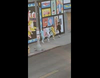 Four men jumpsuit dance graffiti wall sidewalk