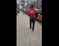 Man plays multiple instrument walks on sidewalk