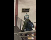 Guy goes downstairs at station in armor helmet 