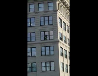 Guy cleans building window no safety rope