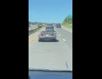 A old school mclaren driving on the freeway with the suicide doors up 
