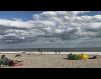 Guy practices kicks in air at the beach, yellow green inflatable lounge chair