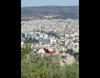 Woman in red satin dress poses at the mountain rocks