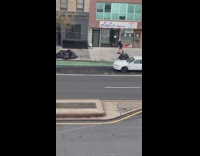 Guy rollerblading on sidewalk holding two paper bags