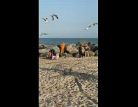 Woman in yellow dress poses at the beach rocks