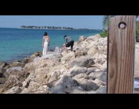 Woman in white dress poses on the beach rocks