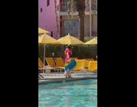 Woman in rainbow colored dress spin by the poolside