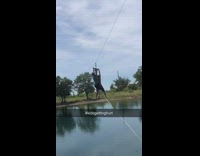 Two boys ride on zipline together, both fall off into water and get caught on rope