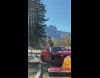 Man shows his butt on top of the red car