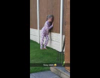 Little girl in backyard looks through fence 