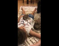 Little girl lays with kitten on stomach 