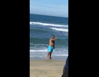 Guy blue shorts hold selfie stick beach