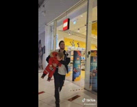 Dad carries son and covers his eyes to run past lego store in mall