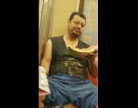 man on train eating half watermelon