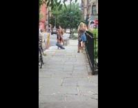 Two girls pose sidewalk black railing plant