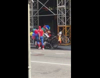 Spiderman rides bike with rainbow balloons and cargo in trunk down the street