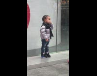 Baby in front of store on the phone on the street