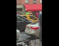 Guy slaps and punches inflatable green trex dinosaur pool floatie on the sidewalk