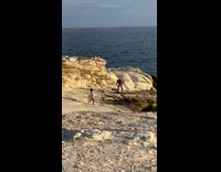 Girl white cardigan dance on rock beach