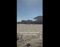 Girl pretends to fall in front of two lifeguards on beach