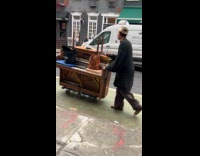 Man push piano with wheels on street