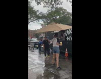 Woman uses table umbrella during storm 