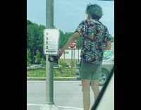 Black hawaiian shirt guy presses crosswalk button 