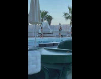 Lady in grey walks slowly next to pool for photos 