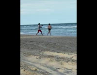 Man in black shorts run white videographer and swims to the beach